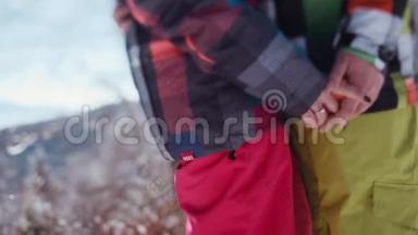 穿着粉红色滑雪服的年轻女孩和穿着绿色冬季运动服装的英俊青年。 别人牵着手